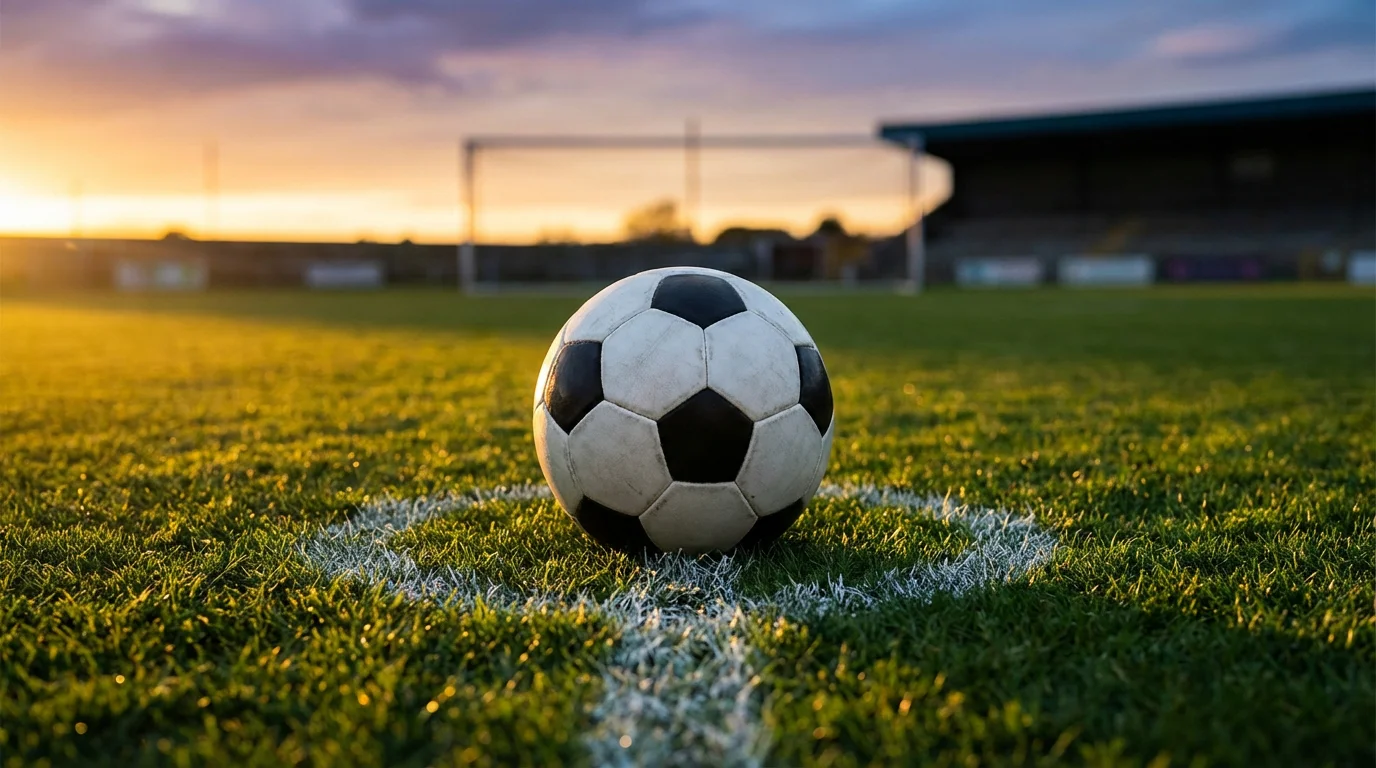 Pallone da calcio su un campo in erba con linea bianca e luce del tramonto